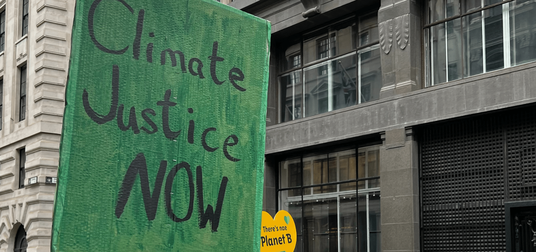 A green placard reads 'Climate Justice Now'